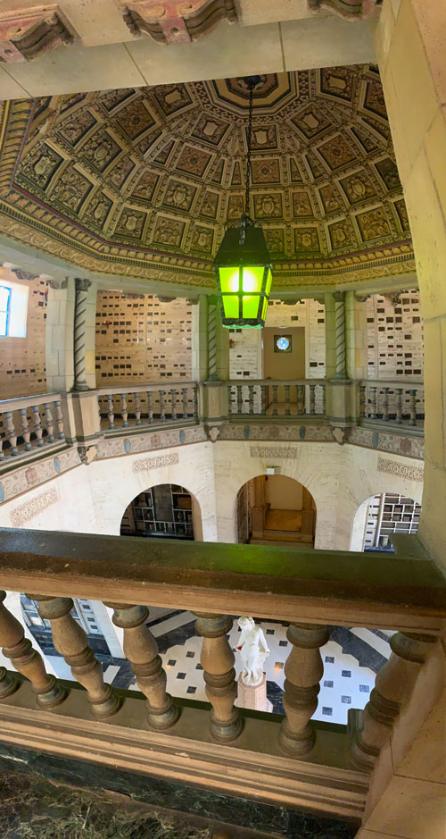 [A greenish lantern hangs from an
ornate dome in the center of an octagonal mausoleum, many walls of which are
filled with graves]