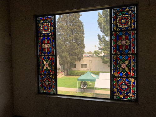 [View out a window lined with
leaded glass toward a casket under a tent in the courtyard.]