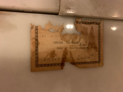 [Stone slab pasted with a now
tattered and stained card with an elaborate border. Card is typed "Crypt" with
an illegible number, then "Reuben Erickson. Date of death: Dec. , 1929"; in
pencil with the kind of handwriting one no longer sees someone has written "2"
beside "Dec.", then crossed that out and written above it "Nov. 28"; underneath
is written, maybe not in the same hand, "Interred - Dec 5"]