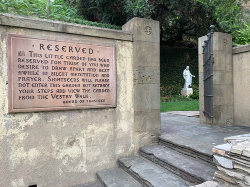 [Stone wall with gate leading to a
small courtyard, next to which is a stone sign, transcribed below.]