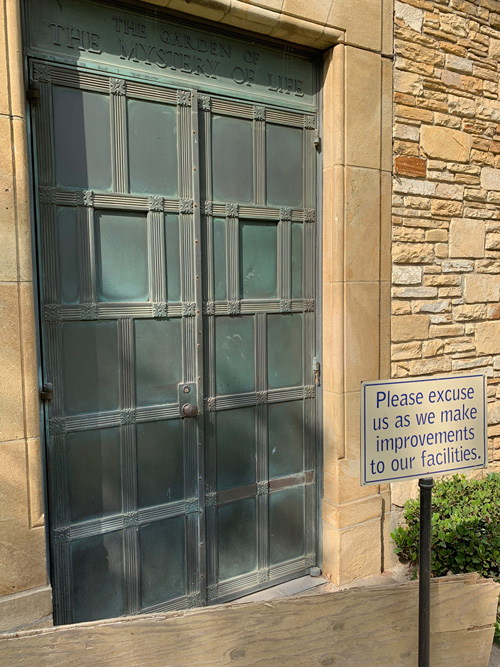 [Oxidized copper door bearing the
words "The Garden of the Mystery of Life," blocked by a wooden barrier, with a
sign standing in front with the words "Please excuse us as we make improvements
to our facilities."]