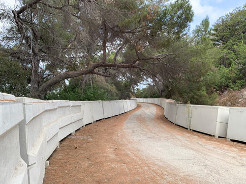 [Gently curving paved road
lined with large concrete boxes.]