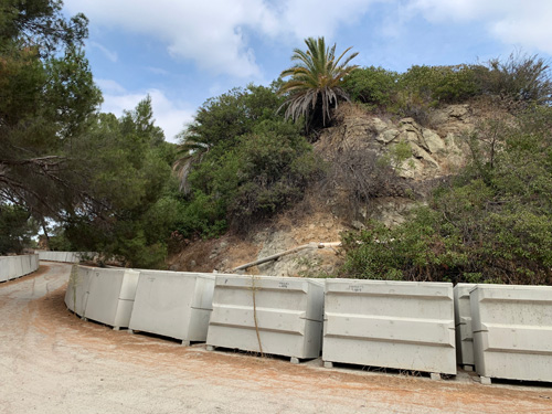 [More concrete burial vaults
surrounding a rocky hill on which plants grow.]