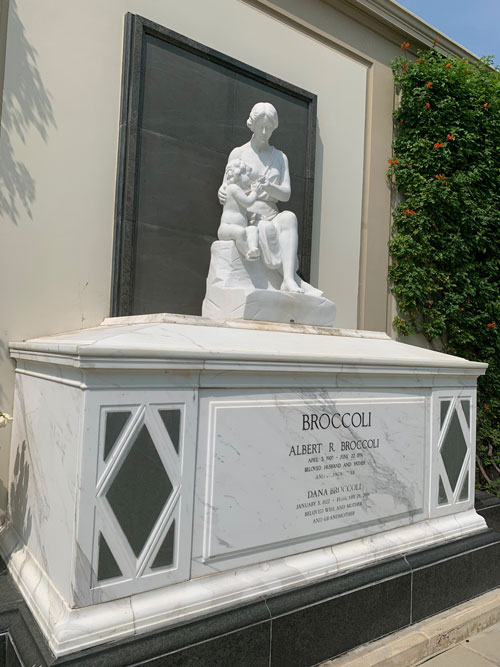 [Marble sarcophagus topped with
a marble statue of a seated robed figure suckling a child; engraved on the front
are the names "Albert R. Broccoli" and, smaller, "Dana Broccoli."]