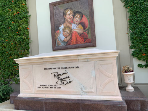 [Marble sarcophagus under a
mosaic representing an oil painting of two children clinging to a woman. Metal
lettering identifies this as the grave of Ronnie James Dio, including a
representation of his signature.]