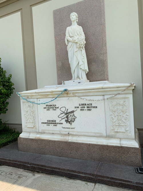 [Marble sarcophagus decorated
with tinsel and topped with marble statue of a robed figure; metal lettering
identifies this as the grave of "Liberace," "George," and "Frances."]