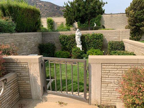 [Small walled courtyard,
entrance to which is controlled by a metal gate, left ajar, which bears a sign,
transcribed below.]
