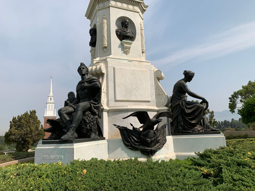 [Bronze and marble sculptural
group with an old colonial-style church steeple in the background.]